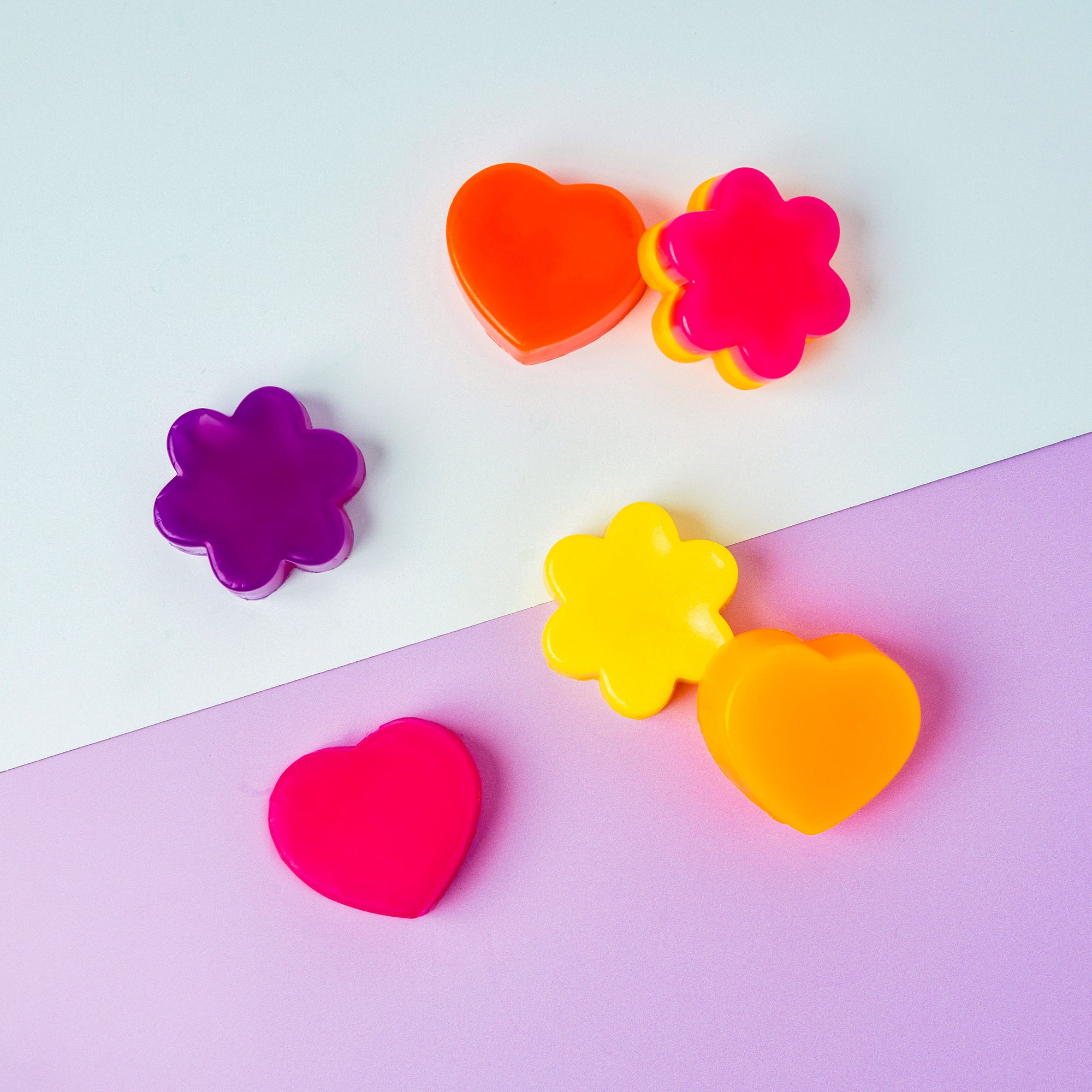 Colorful heart and flower-shaped soaps on a two-tone background
